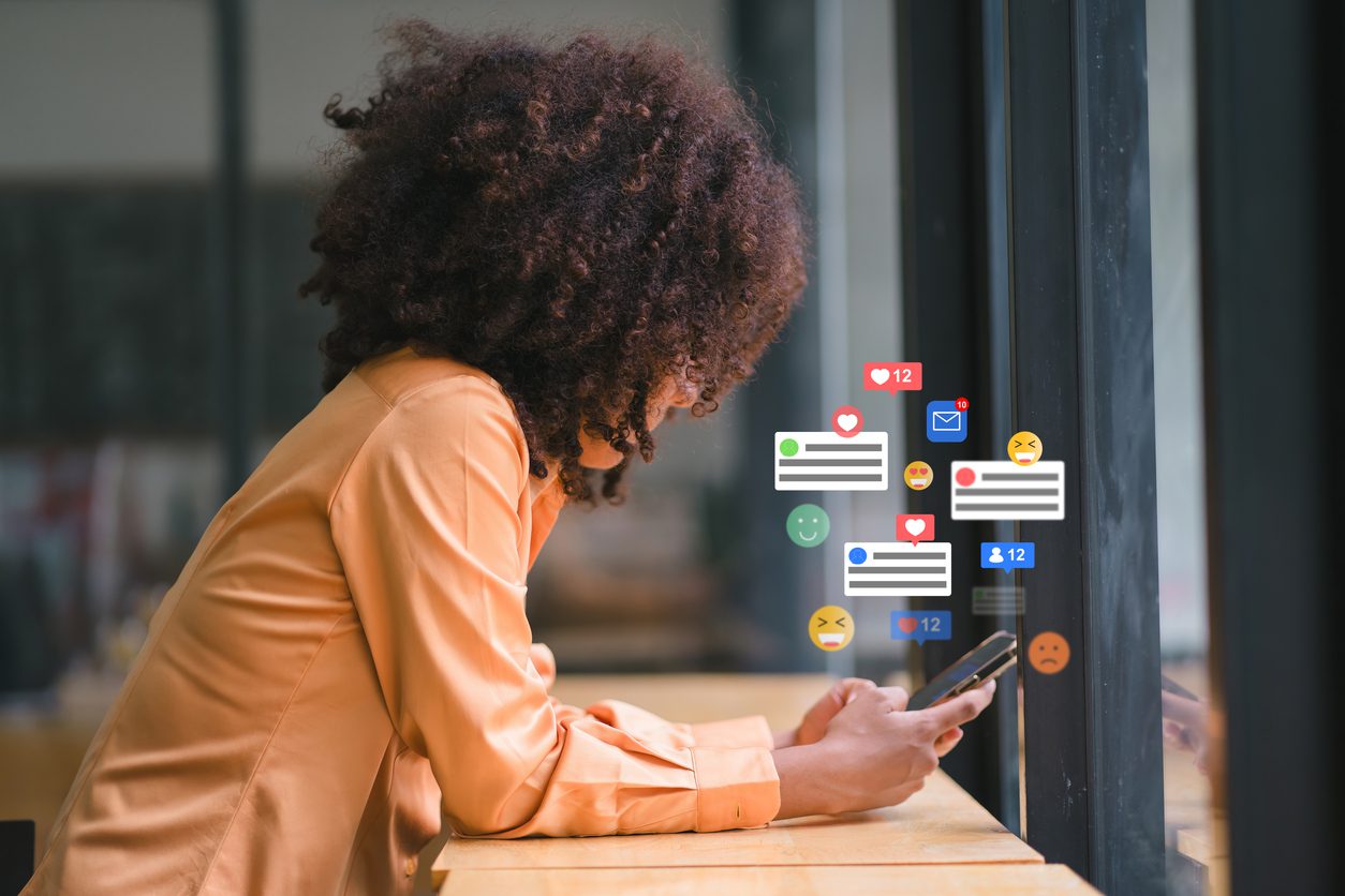 smiling-african-american-businesswoman-engaging-with-social-media-on-smartphone-at-modern-workspace