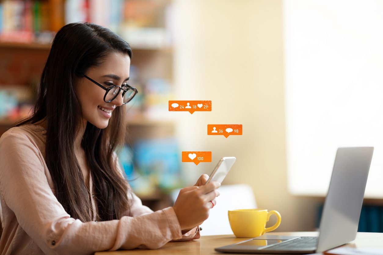 happy-latin-female-blogger-using-smartphone-with-social-media-notification-icons-sitting-in-cafe-free-space