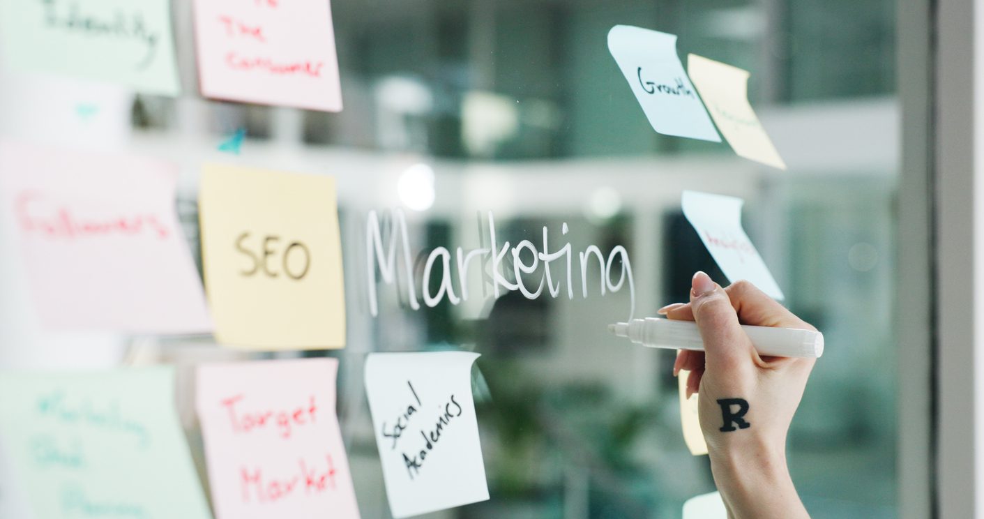 advertising-hands-and-writing-on-glass-wall-for-business-growth-seo-plan-or-target-audience-trends-marketing-increase-awareness-and-person-at-board-with-sticky-note-strategy-or-goal-for-campaign