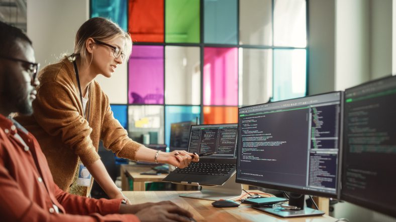 black-programmer-shows-code-on-desktop-computer-to-female-start-up-founder-in-creative-office-space-african-man-and-caucasian-woman-discussing-new-software-features-for-mobile-application